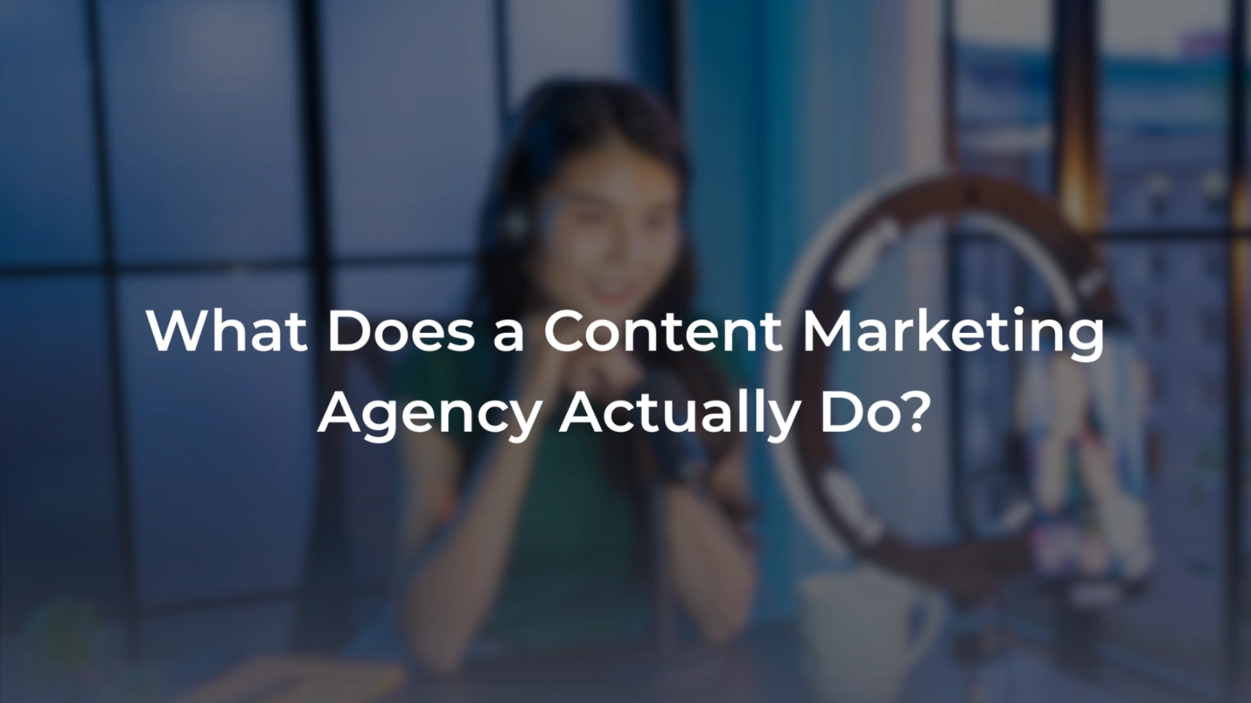 A promotional banner featuring a blurred background of a woman with a headset sitting in front of a ring light recording setup. Overlaid in bold white text is the question: "What Does a Content Marketing Agency Actually Do?". 