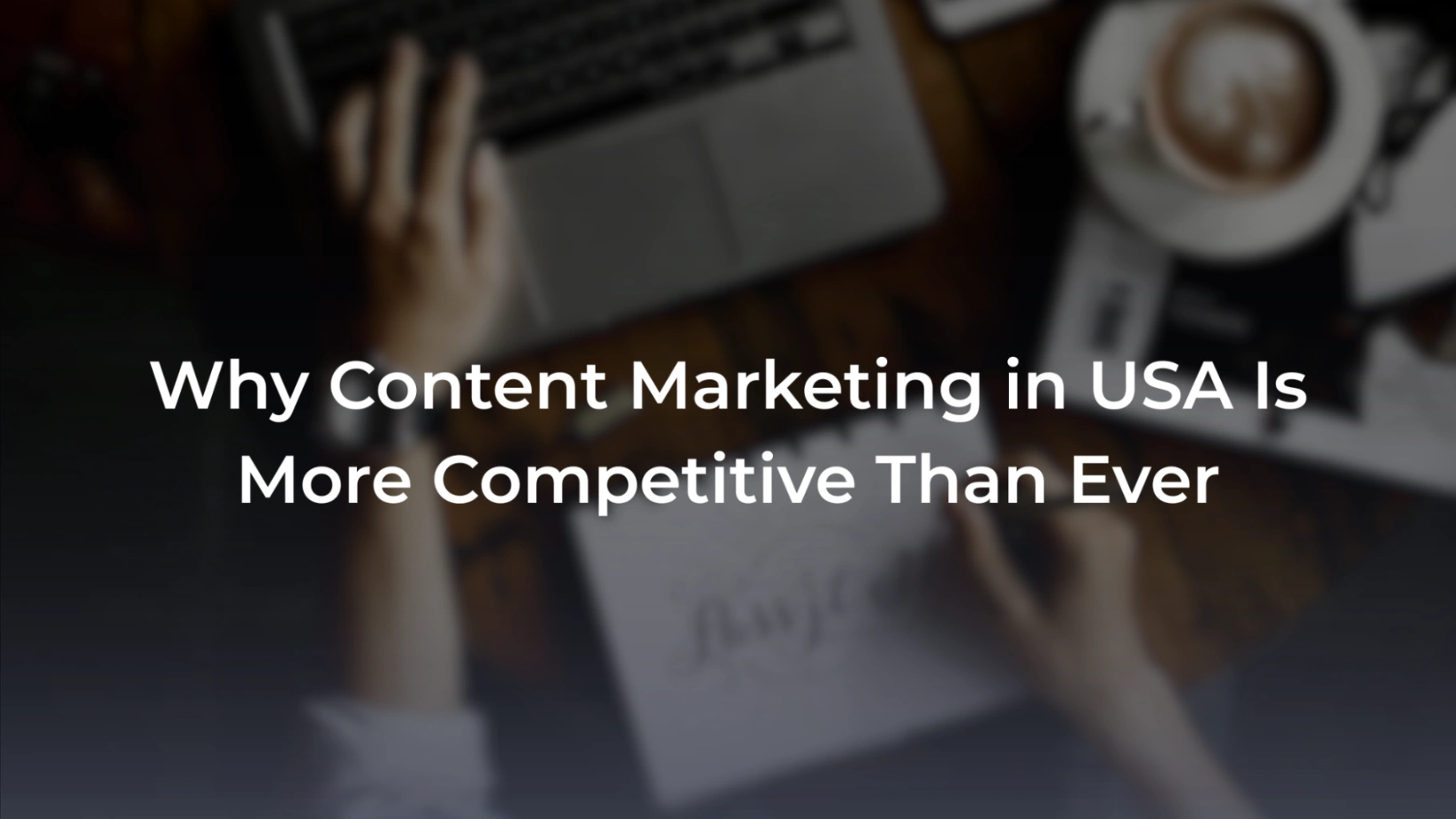 A promotional banner featuring an overhead blurred view of a person using a laptop next to a cup of coffee and a notebook. Overlaid text reads: "Why Content Marketing in USA Is More Competitive Than Ever". 

