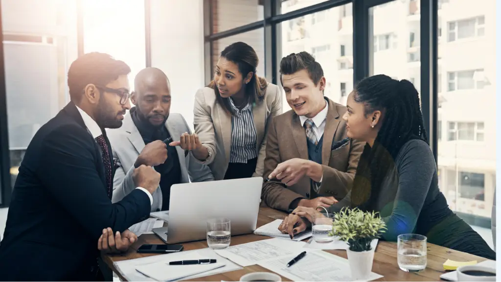 Communication Speed and Workflow Dashboard Integrations A group of business professionals collaborating around a laptop during a meeting, representing teamwork, communication, workflow integration, and efficient dashboard-driven decision-making in a modern workplace.