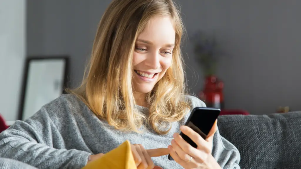 A smiling person uses a smartphone, symbolizing user engagement, search intent, positive digital experiences, and personalized content interactions.