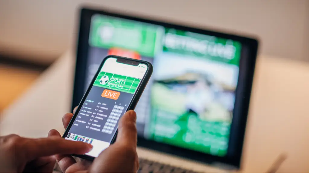 Making It Easy for Mobile Buyers to Complete Purchases A person using a smartphone to access a mobile shopping and live information platform, with a laptop in the background, illustrating mobile commerce, digital transactions, responsive user experiences, and convenient on-the-go purchasing.