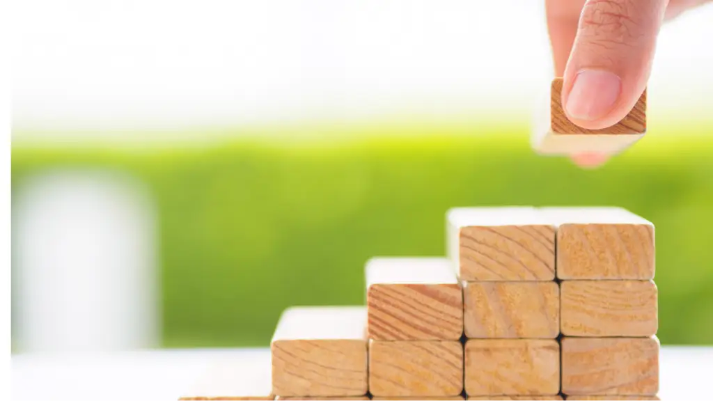 A hand places a wooden block on a growing stack, symbolizing building strong technical foundations, website optimization, and scalable digital growth.