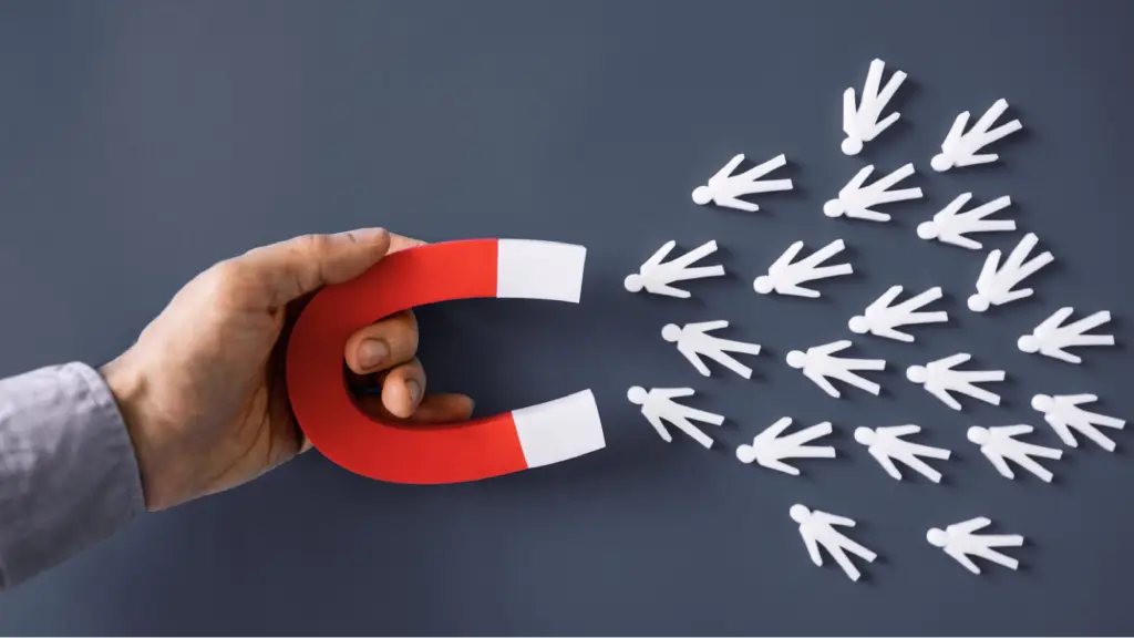 Securing Lead Attribution and Platform Connectivity A hand holding a magnet attracting multiple person icons, representing lead generation, customer acquisition, lead attribution, and platform connectivity in digital marketing and business growth strategies.
