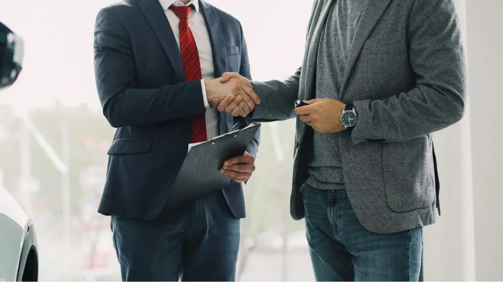 Two business professionals shake hands while one holds a clipboard, symbolizing a successful business deal, client partnership, trust, and long-term professional collaboration.