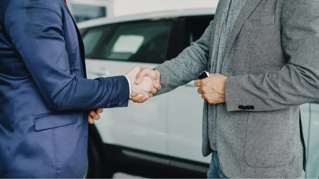 Securing Long-Term Client Loyalty A close-up of two business professionals shaking hands in front of a vehicle, symbolizing trust, long-term client loyalty, successful partnerships, and strong business relationships built through mutual confidence and collaboration.