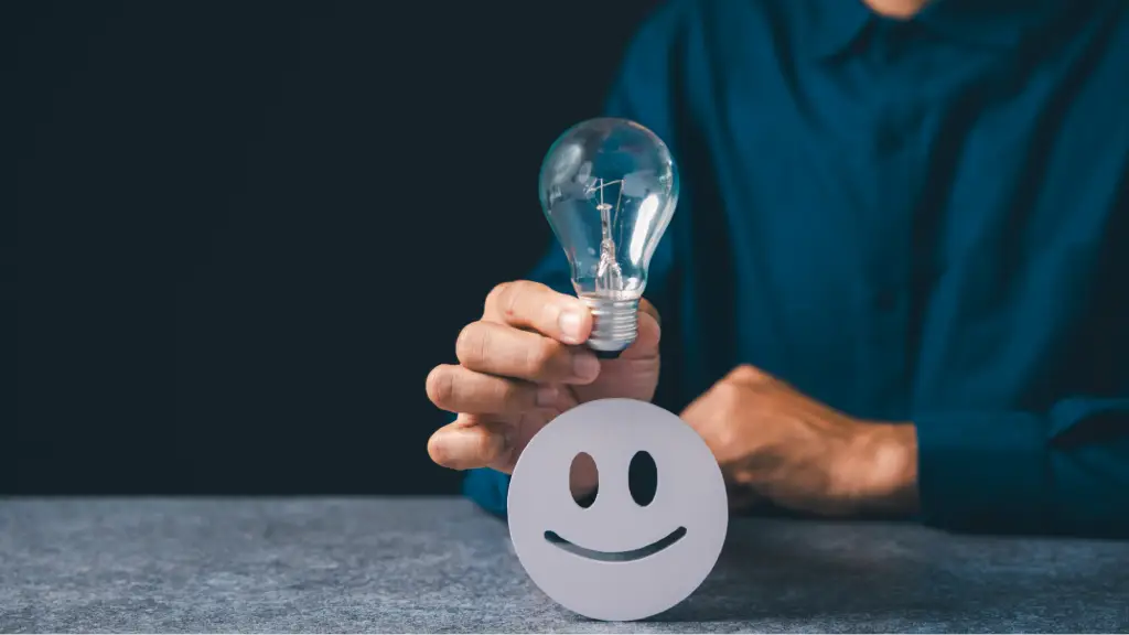 Securing Long-Term Client Loyalty (4) A person holds a light bulb above a smiling face icon against a dark background, symbolizing creative ideas, customer satisfaction, innovation, and positive business solutions.