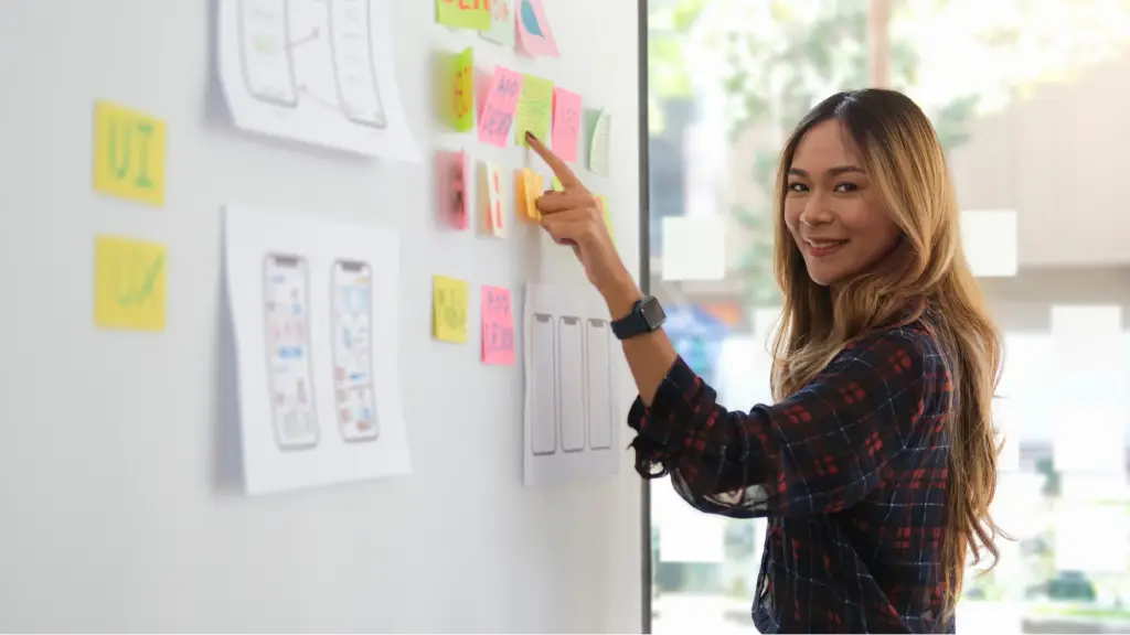 A person arranging colorful sticky notes and mobile app wireframes on a planning board, representing collaboration, project management, user experience design, and a structured three-party operational workflow.