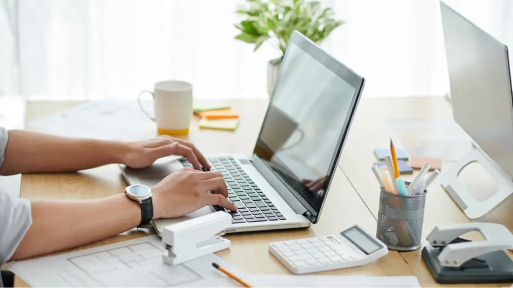 A person types on a laptop at a clean workspace, representing answer engine optimization, digital content creation, and online research.