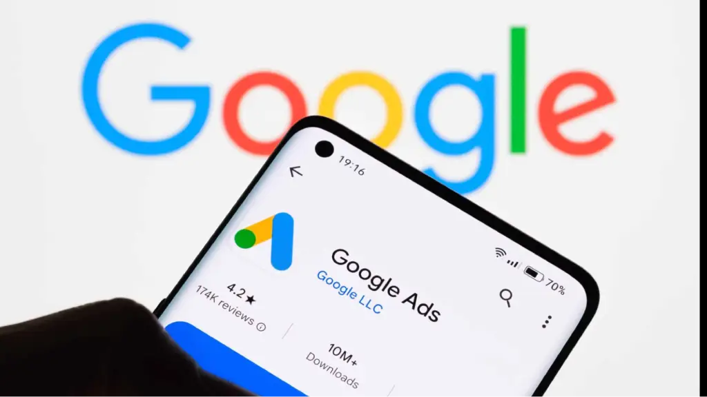 A smartphone displays the Google Ads app with the Google logo in the background, symbolizing ecommerce advertising, paid search campaigns, and online business growth.