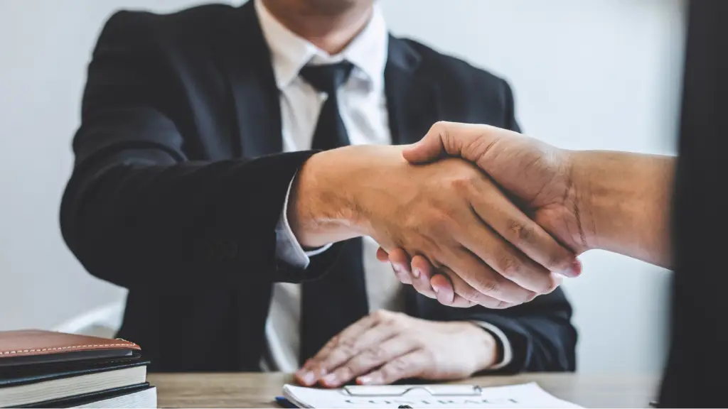 How White Label Partnerships Improve Client Retention Two professionals shake hands across a desk, symbolizing successful business partnerships, client trust, and long-term client retention through collaboration.