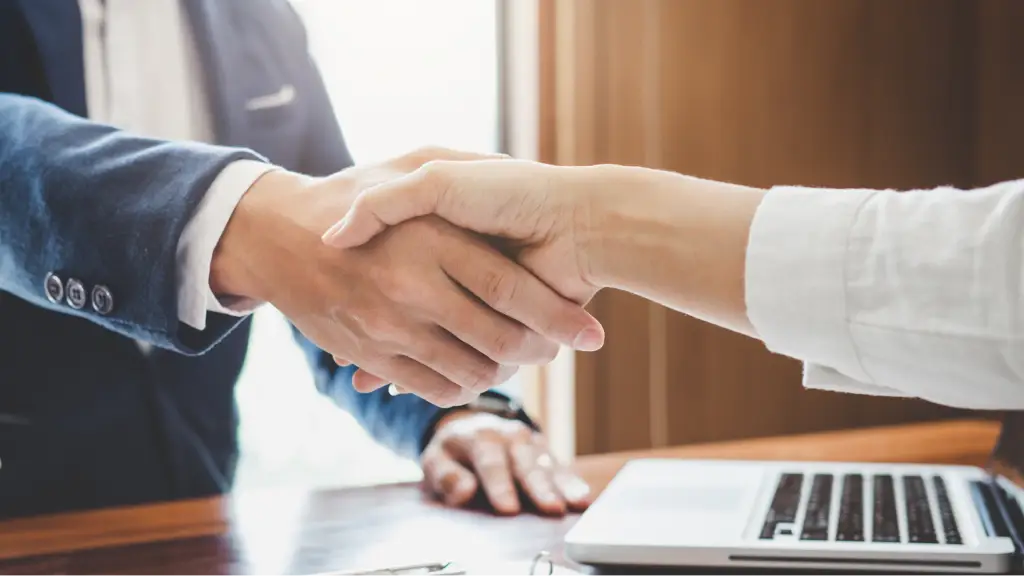 Why Agencies Choose to Resell PPC Services Two professionals shake hands across a desk, representing successful business partnerships, client collaboration, and agencies expanding services by reselling PPC solutions.